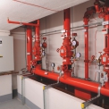 V místnosti řídících ventilů jsou na horizontálním rozdělovacím potrubí nad záchytnou vanou umístěny tři mokré ventilové stanice Victaulic.